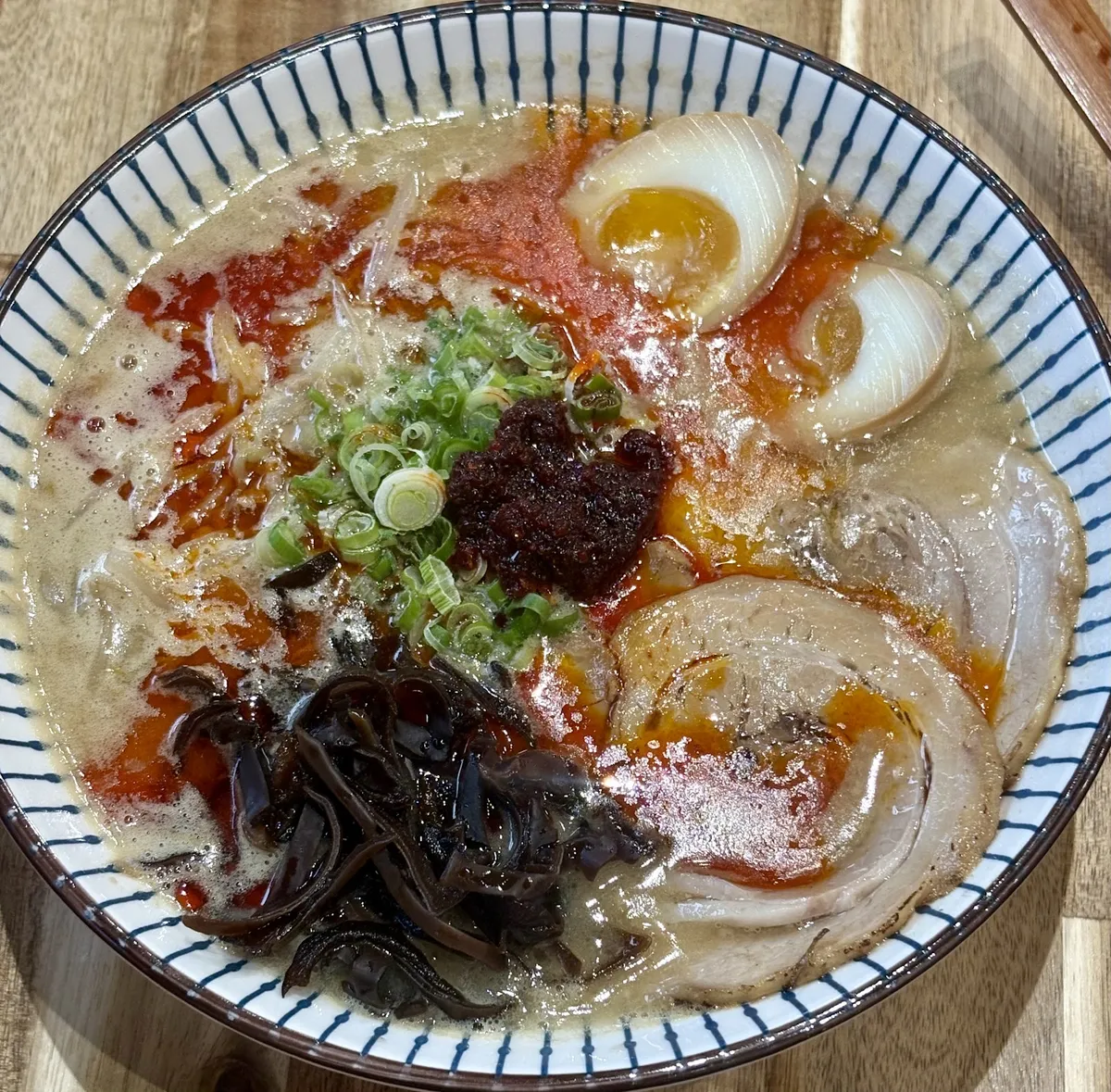 Spicy ramen bowl with chashu, soft egg, and scallions